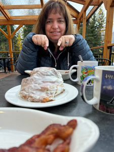 Ruth pointing out size of Alaska sized cinnamon roll